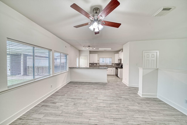 unfurnished living room with track lighting, light wood-style floors, baseboards, visible vents, and a ceiling fan