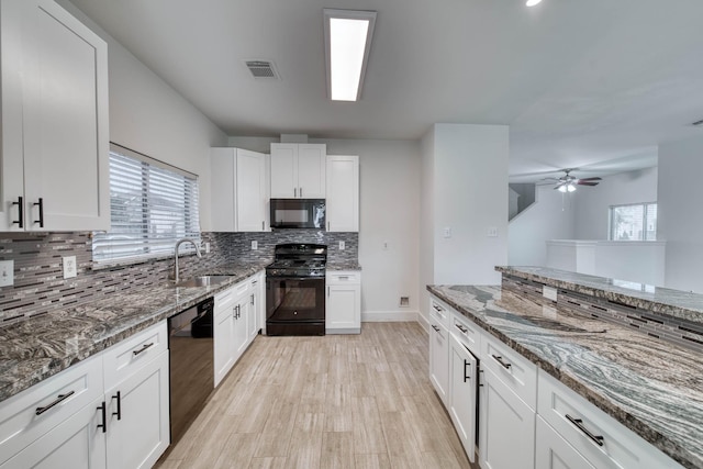 kitchen with black appliances, visible vents, white cabinets, and a sink