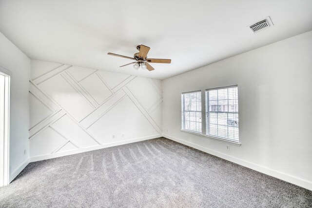spare room with carpet flooring, a ceiling fan, visible vents, and baseboards