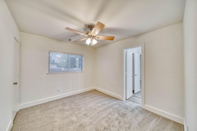 unfurnished room featuring light colored carpet, a ceiling fan, and baseboards