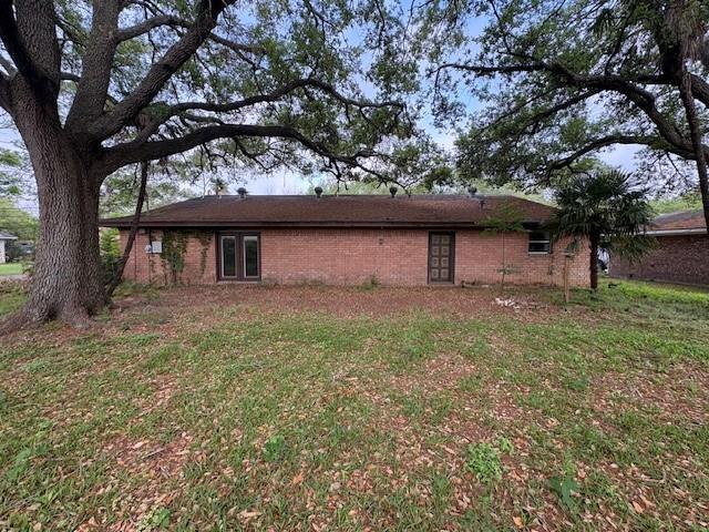 view of side of property with brick siding and a yard