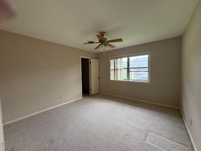 spare room featuring ceiling fan, light colored carpet, and baseboards
