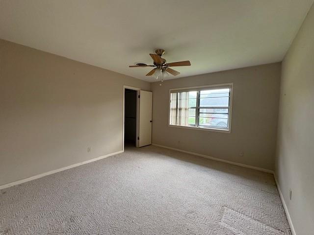 unfurnished room with light colored carpet, baseboards, and a ceiling fan