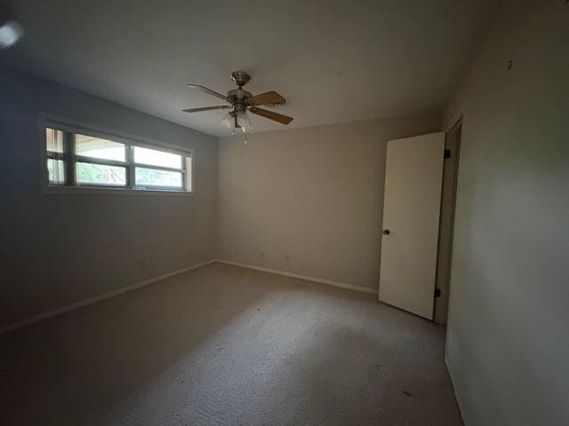 unfurnished room featuring light colored carpet, baseboards, and a ceiling fan