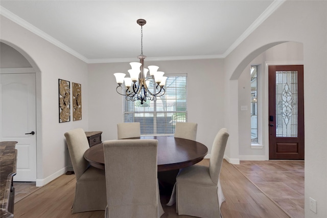 dining room with crown molding, arched walkways, an inviting chandelier, and light wood-style floors