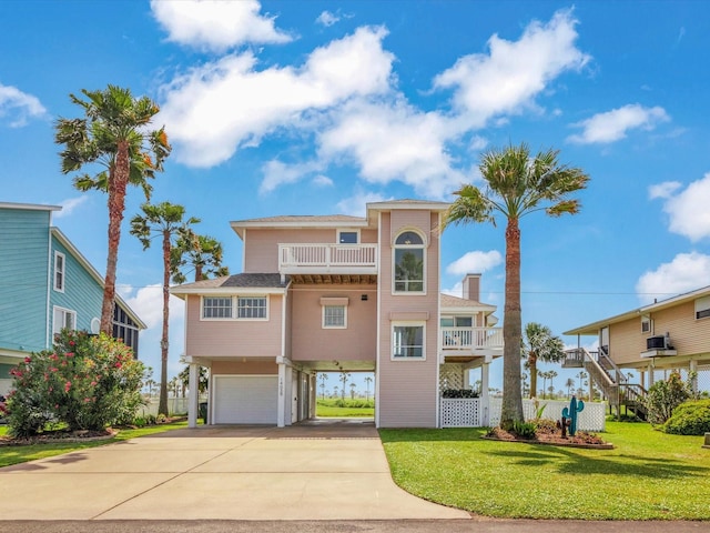 coastal home with an attached garage, a balcony, a front yard, and concrete driveway