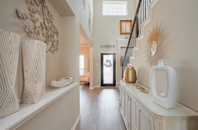 entrance foyer with light wood-type flooring, a high ceiling, baseboards, and stairway