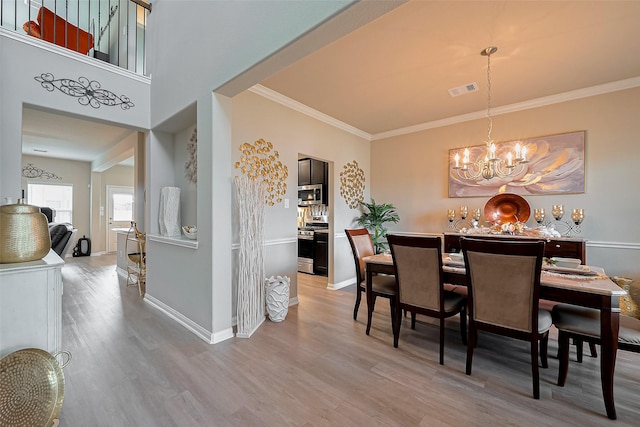 dining space featuring baseboards, an inviting chandelier, ornamental molding, visible vents, and wood finished floors
