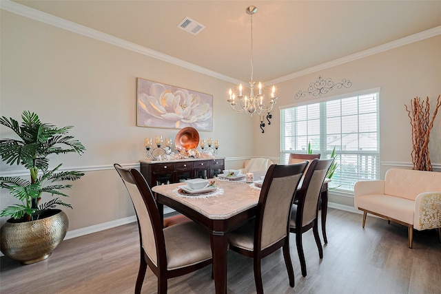 dining area with ornamental molding, visible vents, a notable chandelier, and wood finished floors