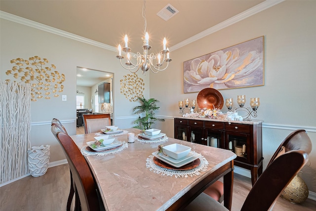 dining room featuring visible vents, baseboards, ornamental molding, a chandelier, and light wood-style flooring