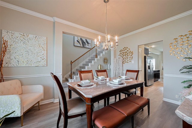 dining area featuring stairs, a notable chandelier, light wood-style floors, and crown molding