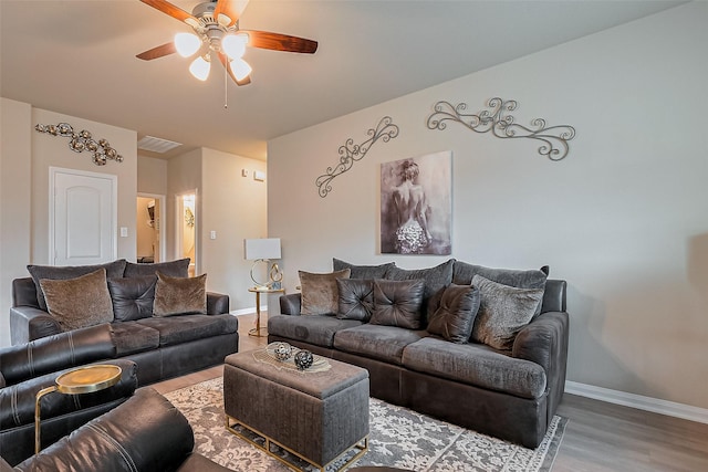 living area with visible vents, baseboards, wood finished floors, and ceiling fan