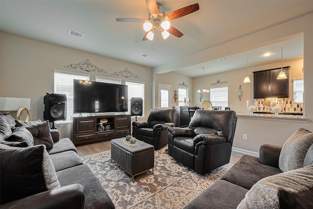 living room with light wood finished floors, ceiling fan, baseboards, and visible vents
