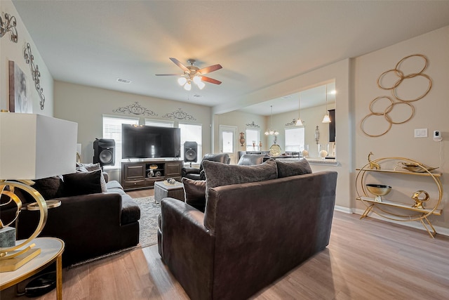 living area with light wood-style flooring, ceiling fan, baseboards, and visible vents
