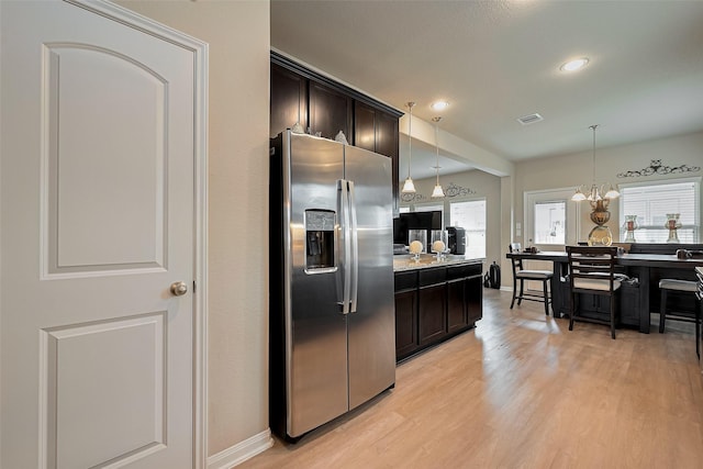 kitchen featuring visible vents, stainless steel refrigerator with ice dispenser, light wood-type flooring, dark brown cabinets, and pendant lighting