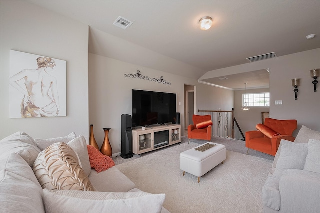 living area featuring visible vents, light colored carpet, and lofted ceiling