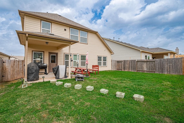 rear view of house featuring a yard, a patio, a fenced backyard, and an outdoor fire pit