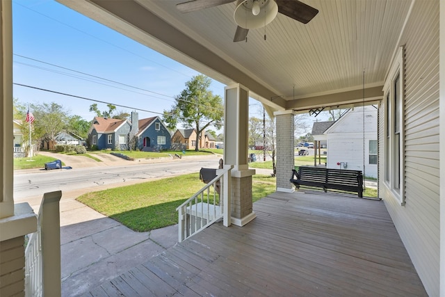 wooden terrace featuring a residential view, a ceiling fan, a yard, and covered porch