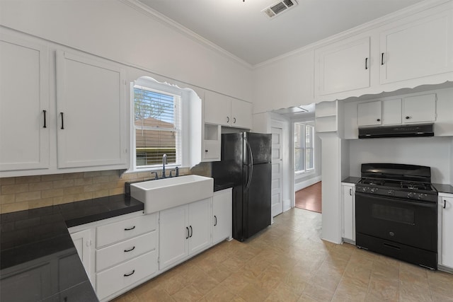 kitchen with a sink, visible vents, dark countertops, under cabinet range hood, and black appliances