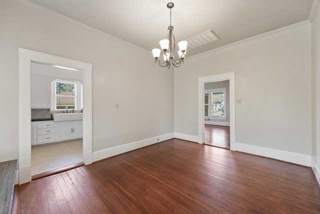 empty room with crown molding, a notable chandelier, baseboards, and dark wood finished floors