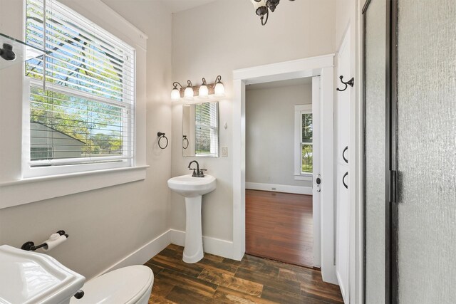 half bathroom with baseboards, wood finished floors, and toilet