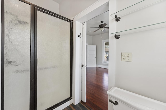bathroom featuring toilet, a stall shower, a ceiling fan, and wood finished floors
