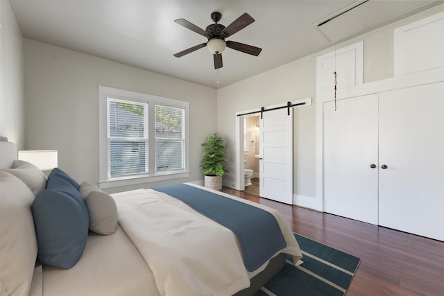 bedroom featuring a barn door, attic access, dark wood-type flooring, a ceiling fan, and ensuite bath