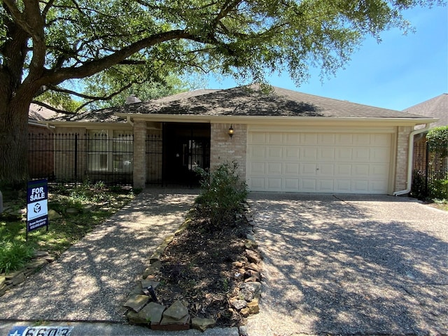 ranch-style home featuring brick siding, an attached garage, concrete driveway, and fence
