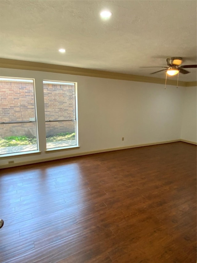 spare room with a ceiling fan, baseboards, and dark wood-style flooring