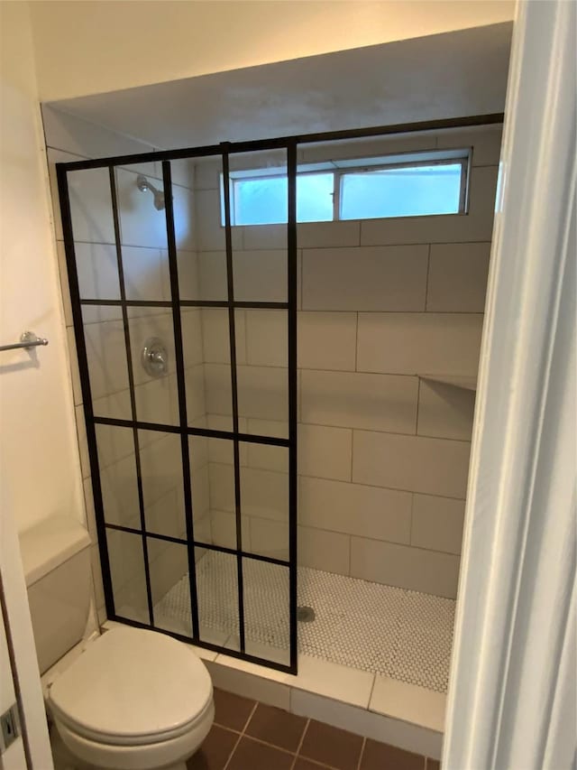 full bathroom featuring toilet, a shower stall, tile patterned floors, and a healthy amount of sunlight