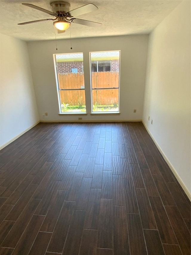 spare room with ceiling fan, baseboards, and dark wood-style flooring