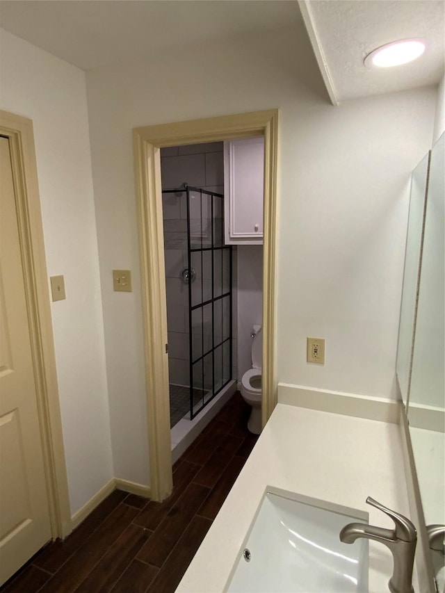 full bathroom with a shower stall, toilet, vanity, baseboards, and wood finish floors