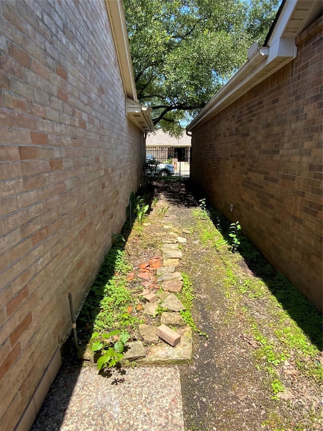 view of side of home with brick siding and fence