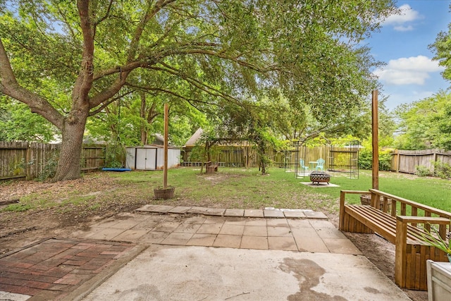 21263 Park Bluff Dr, Katy, TX 77450 - view of patio / terrace with an outdoor structure, a fire pit, a fenced backyard, and a storage unit