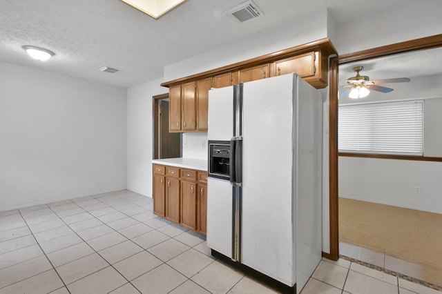 kitchen featuring light countertops, visible vents, a ceiling fan, light tile patterned floors, and white fridge with ice dispenser