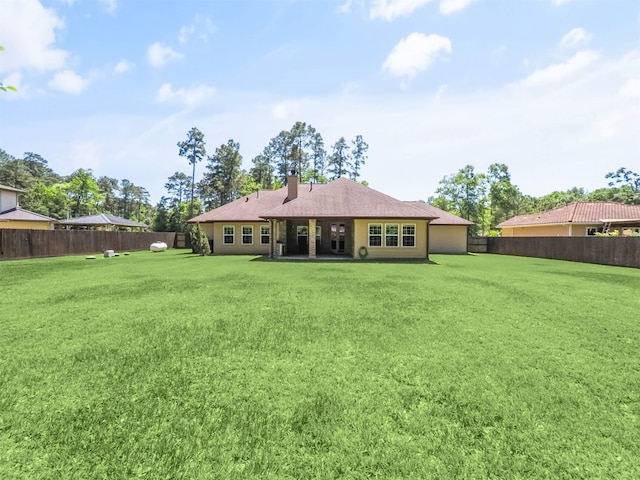 19507 Balsas Dr, Porter, TX 77365 - back of house with a chimney, a fenced backyard, and a lawn