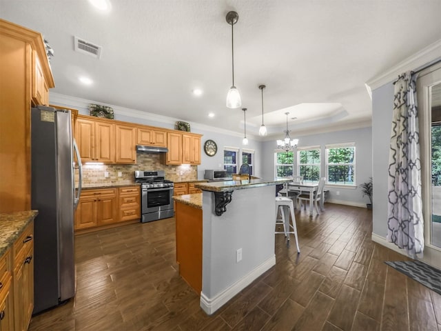 19507 Balsas Dr, Porter, TX 77365 - kitchen featuring dark wood finished floors, a kitchen breakfast bar, visible vents, appliances with stainless steel finishes, and backsplash