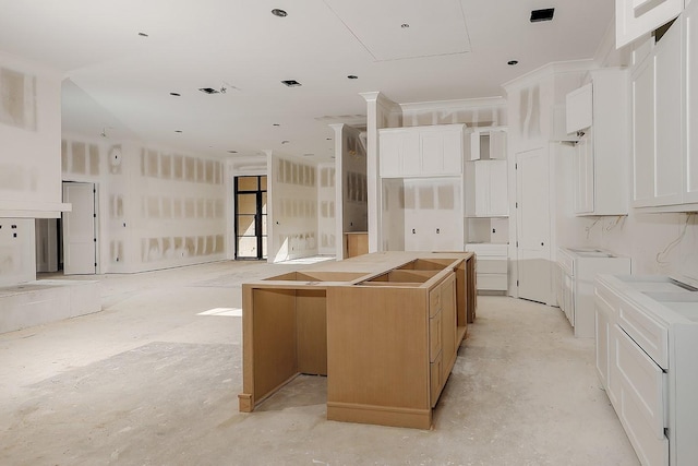 kitchen with open floor plan, a center island, white cabinets, visible vents, and concrete flooring