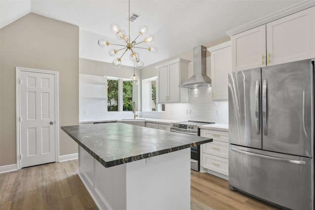 kitchen with an inviting chandelier, wall chimney exhaust hood, open shelves, vaulted ceiling, and stainless steel appliances