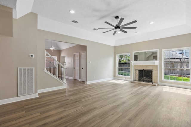 unfurnished living room featuring stairs, visible vents, baseboards, and ceiling fan