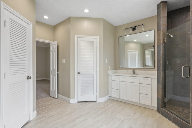 bathroom featuring a shower stall, a closet, vanity, and baseboards