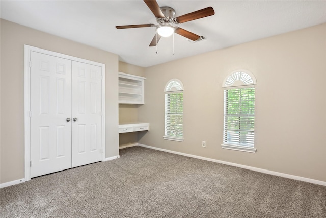 unfurnished bedroom with a closet, a ceiling fan, visible vents, carpet flooring, and baseboards