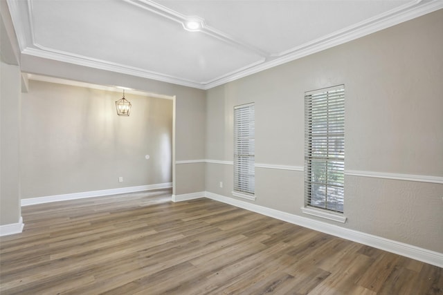 unfurnished room featuring wood finished floors, an inviting chandelier, baseboards, and ornamental molding