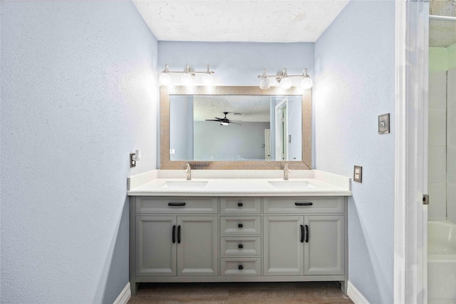full bath featuring a sink, a textured wall, and baseboards