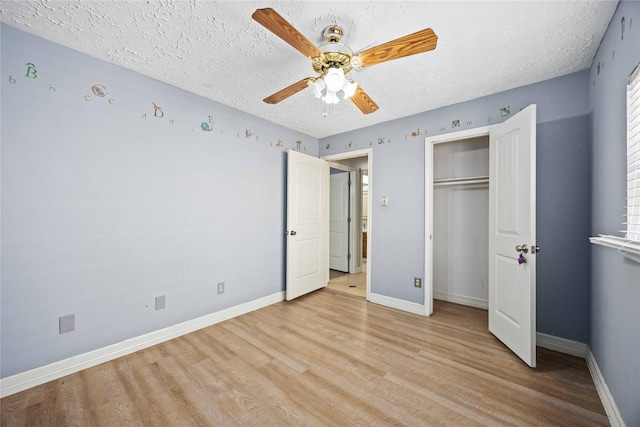 unfurnished bedroom featuring light wood-style floors, baseboards, and a textured ceiling