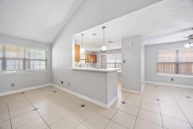 kitchen with a wealth of natural light, light tile patterned floors, a textured ceiling, and brown cabinetry