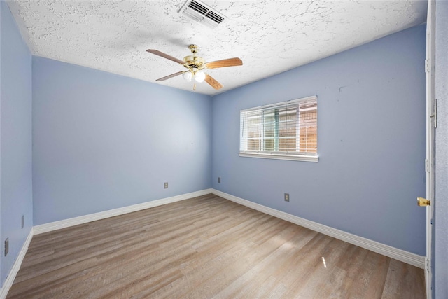 empty room featuring wood finished floors, ceiling fan, baseboards, and visible vents