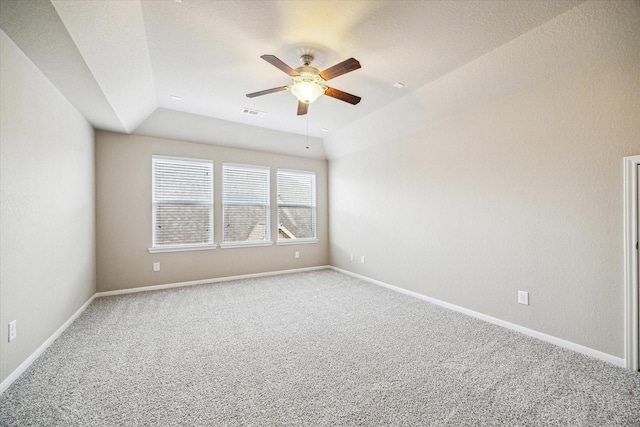 carpeted spare room with baseboards, vaulted ceiling, visible vents, and ceiling fan