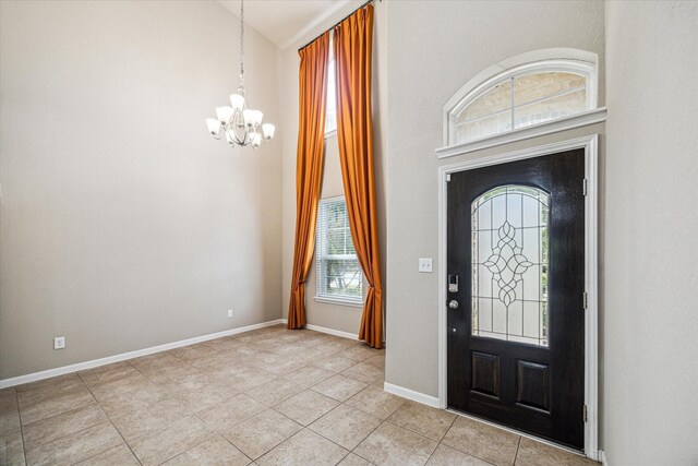 foyer featuring plenty of natural light, baseboards, high vaulted ceiling, and a chandelier