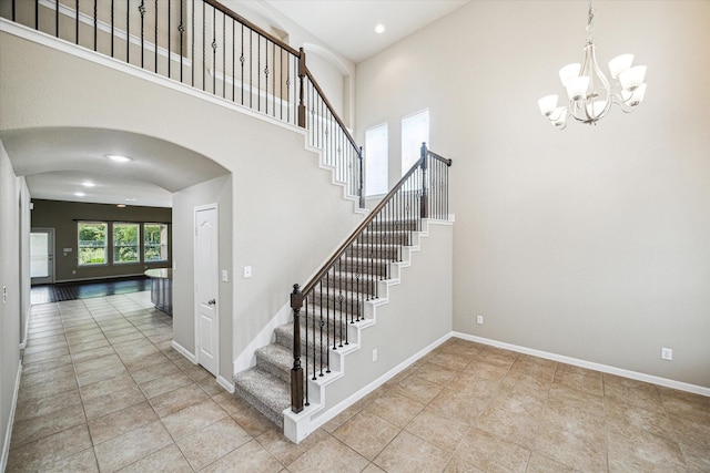 staircase featuring an inviting chandelier, arched walkways, recessed lighting, and tile patterned floors